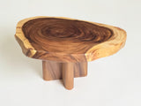 A rustic wooden side table with a natural live-edge tree top and three short block legs, shown on a plain white background.