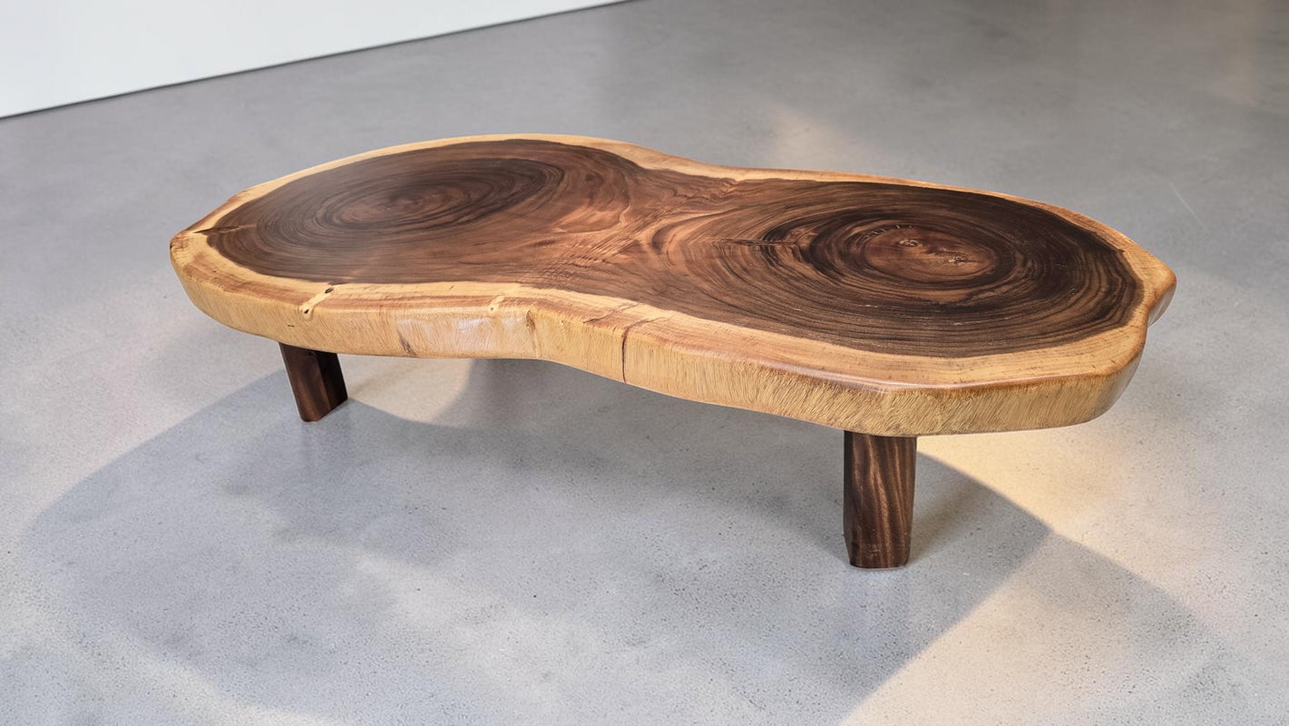 Handcrafted live edge Suar wood coffee table with solid hardwood legs at an angled front view.