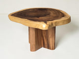 A rustic live-edge wooden table with a natural irregular top and three sturdy block legs, shown on a clean white background.