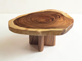 A rustic live-edge wooden table with a natural tree slice top and three short block legs, photographed on a clean white studio background.