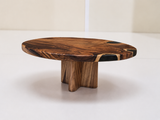 A round wooden coffee table with a thick live-edge top and three chunky block legs, shown on a clean white studio floor.
